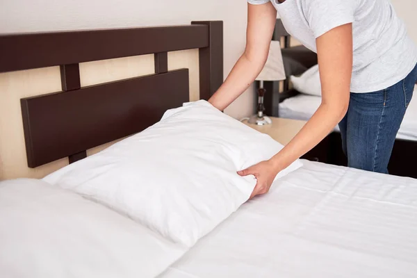 Обрезанное изображение женских рук, исправленная подушка на кровати дома или — стоковое фото