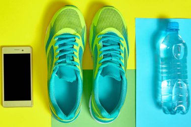 Spor ayakkabı, mobil akıllı telefon ve renkli mavi su, yello
