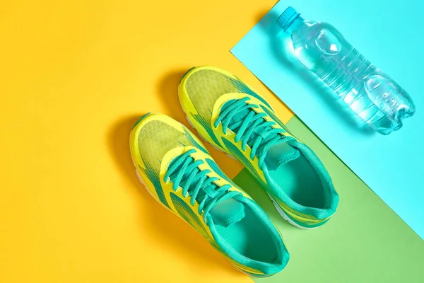 Par de zapatillas deportivas y agua sobre fondo colorido. Ne. — Foto de Stock