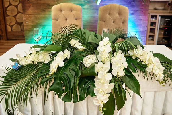 Exuberante arreglo floral de orquídeas y hojas de monstera en boda — Foto de Stock