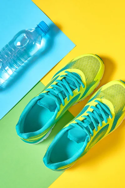 Pair of sport running shoes and water on colorful background. Ne — Stock Photo, Image