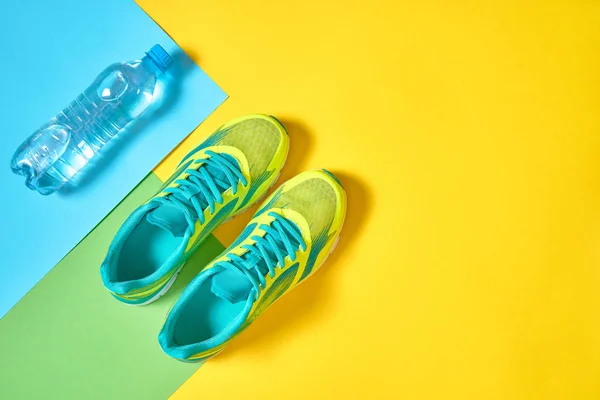 Par de zapatillas deportivas y agua sobre fondo colorido. Ne. — Foto de Stock