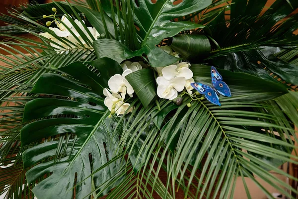 Exuberante arreglo floral de orquídeas y hojas de monstera en boda —  Fotos de Stock