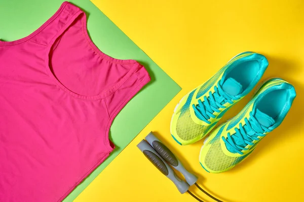 Sport shoes, female top bra and skipping rope on colorful yellow