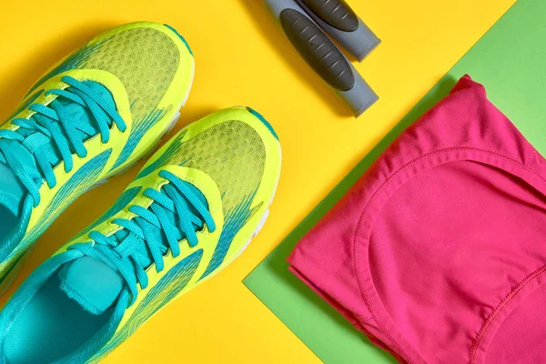 Sport shoes, female top bra and skipping rope on colorful yellow