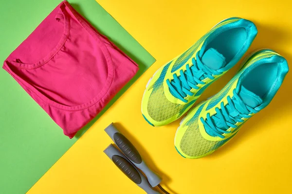 Sport shoes, female top bra and skipping rope on colorful yellow