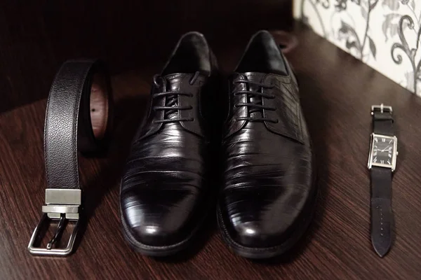 Siyah erkek ayakkabıları, kemer ve ahşap masa bac saatler yakın — Stok fotoğraf