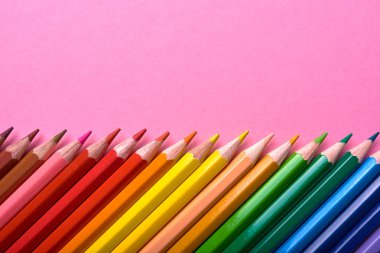 Pembe pastel arka plan üzerinde renkli kalemler, yakın. Colorf seti