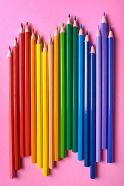 Pembe pastel arka plan üzerinde gökkuşağı renkleri renkli kalemler, cl