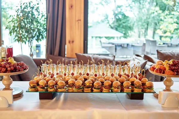 Buffet table with mini hamburgers and sliced fruits at luxury we