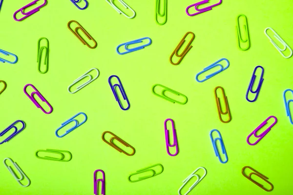 Colorful paper clips on lime green background, copy space. Top v