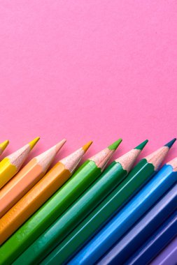 Pembe pastel arka plan üzerinde renkli kalemler, yakın. Colorf seti