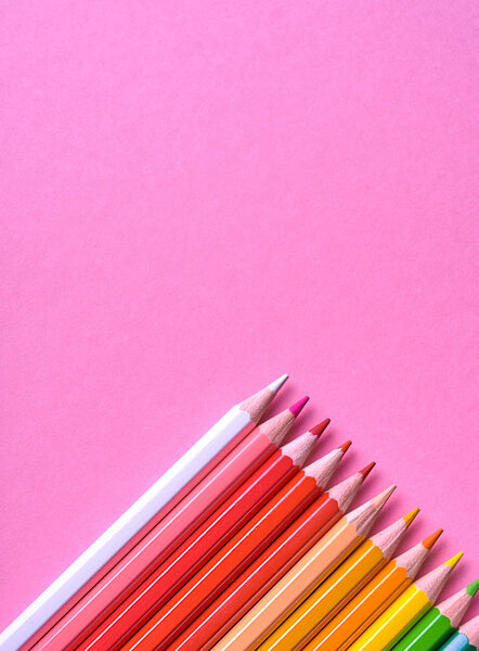 Color pencils on pink pastel background, close up. Set of colorf