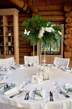 Çatal bıçak takımı, şarap kadehleri ve çiçek süslemeleri ile masa ayarı o