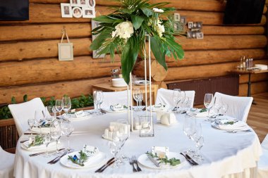 Çatal bıçak takımı, şarap kadehleri ve çiçek süslemeleri ile masa ayarı o