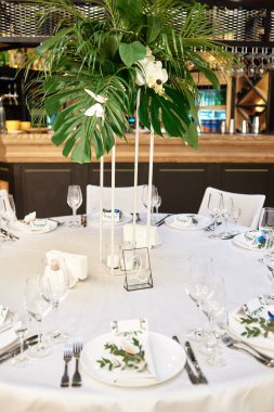 Çatal bıçak takımı, şarap kadehleri ve çiçek süslemeleri ile masa ayarı o