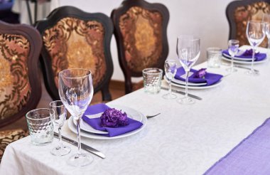 Beyaz tabaklar, çiçekler, şarap kadehleri ve çatal bıçak takımı ile masa ayarı