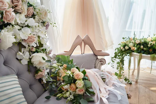 Люксовые бежевые туфли на высоких каблуках и свадебный букет в размытом цвете — стоковое фото