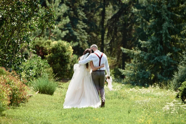 Feliz novia y novio abrazando y caminando en el jardín en la boda d —  Fotos de Stock