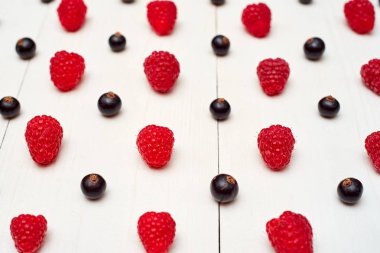 Olgun tatlı ahududu ve beyaz ahşap backgroun siyah frenk üzümü