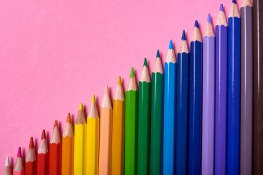 Pembe pastel arka plan üzerinde renkli kalemler, yakın. Colorf seti