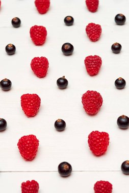 Olgun tatlı ahududu ve beyaz ahşap backgroun siyah frenk üzümü