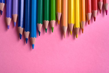 Pembe pastel arka plan üzerinde renkli kalemler, yakın. Colorf seti