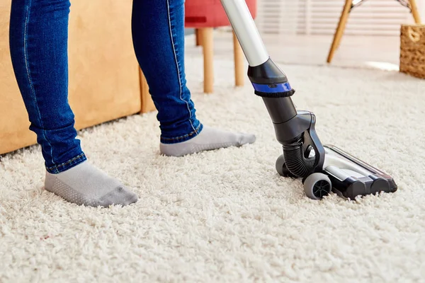 Close up of young woman in jeans cleaning carpet with vacuum cle — Stock Photo, Image