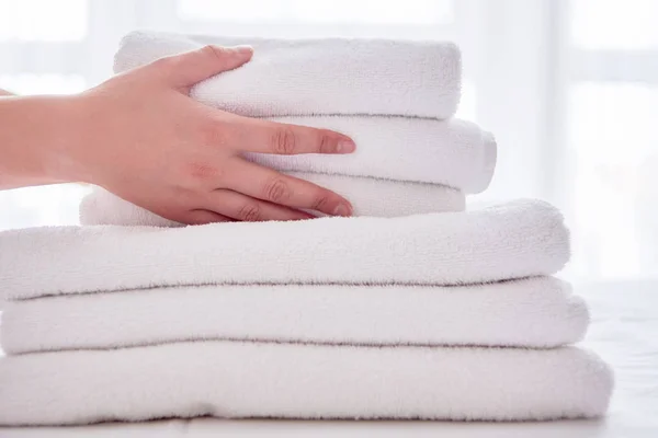 Woman putting stack of fresh white bath clean towels on bed shee — Stock Photo, Image