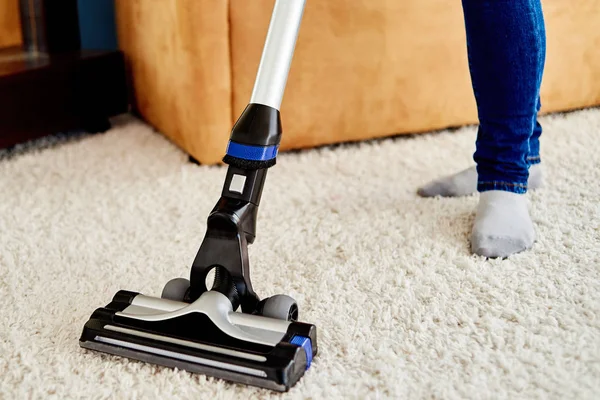 Nahaufnahme einer jungen Frau in Jeans, die Teppich mit Staubsauger putzt — Stockfoto