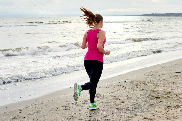 Widok z tyłu atletyczna kobieta działa na plaży morskiej, przestrzeń kopiowania. Fe — Zdjęcie stockowe