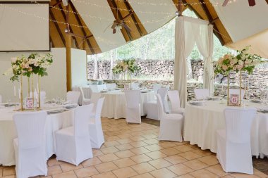 Masa seti, köpüklü şarap bardakları ve çatal bıçak takımı, kopyalama alanı. Lüks düğün resepsiyonunda. Restoranda verilen ziyafet için yuvarlak masa ve beyaz sandalyeler.