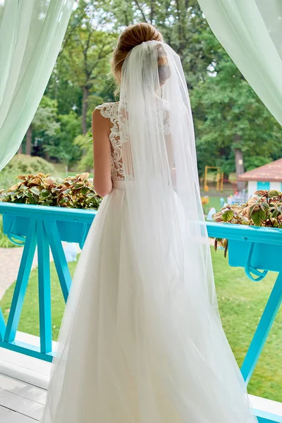 テラス屋外 バックビュー コピースペースに立って花束と白いウェディングドレスとベールの美しい花嫁 花嫁の朝 — ストック写真