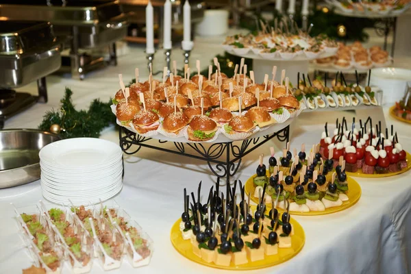 Buffet table with mini hamburgers, snacks, canape and appetizers at luxury wedding reception, copy space. Serving food and appetizers at restaurant. Catering banquet table