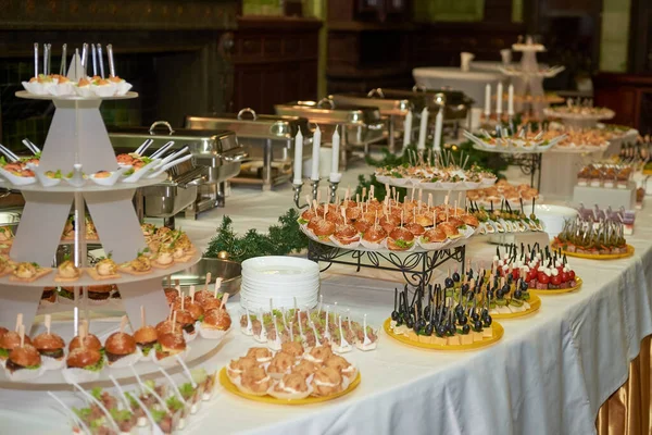 Buffet table with mini hamburgers, snacks, canape and appetizers at luxury wedding reception, copy space. Serving food and appetizers at restaurant. Catering banquet table