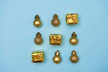 Altın parıltılı süslemeleri ve pastel mavi arka planda hediyeleri olan yaratıcı Noel deseni, kopyalama alanı. Minimal, kış, yeni yıl konsepti. Üst manzara, düz uzanma