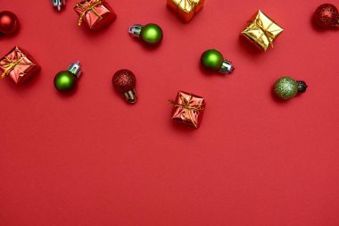 Kırmızı ve yeşil mücevherleri olan yaratıcı Noel deseni ve kırmızı arka planda hediyeler, kopyalama alanı. Minimal, kış, yeni yıl konsepti. Üst manzara, düz uzanma