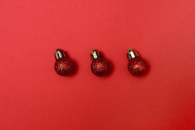 Kırmızı arka planda kırmızı parlak mücevherleri olan yaratıcı Noel deseni, kopyalama alanı. Minimal, kış, yeni yıl konsepti. Üst manzara, düz uzanma
