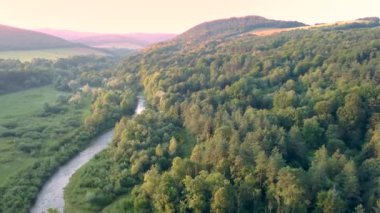 Nehir ve yeşil tepelerin havadan görüntüleri.