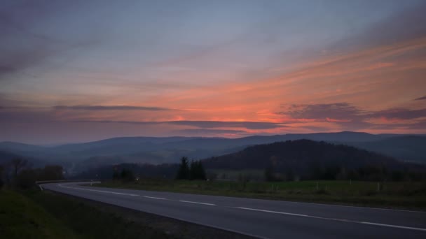 丘の間の道路上の車 カラフルな空と美しい夕日 — ストック動画