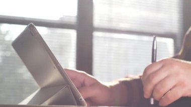 Tablet kullanan bir adam. Tablet üzerinde çalışan kişinin görüntülerini kapat.