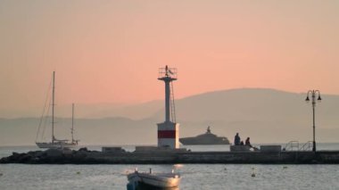 Korfu, Yunanistan 'da gün batımında deniz koyunda teknesi olan iskelede deniz feneri.