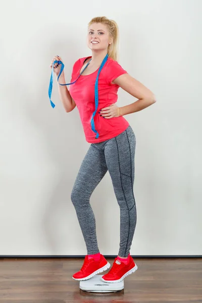 健康生活スタイル 制御体コンセプトに合わせて スポーツウェア レギンス 重量機械保持測定テープの上に立ってのトレーナーを着ている女性 — ストック写真