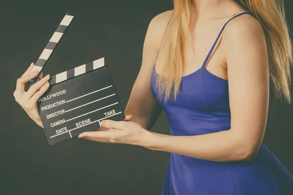 Woman holding professional film slate, movie clapper board. Hollywood production objects concept. Studio shot on black background.