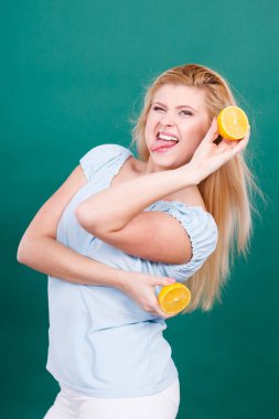 Genç kız holding iki halfs sarı limon narenciye meyve ellerini, koyu yeşil üzerinde gülümseyen kadın. Sağlıklı beslenme beslenme.