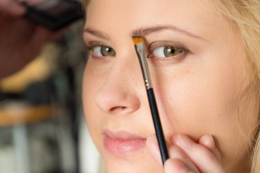 Kozmetik, makyaj, güzellik kavramı. Yapılması, ona kaşları makyaj almak kadın profesyonel fırça, closeup ile gölge uygulama.