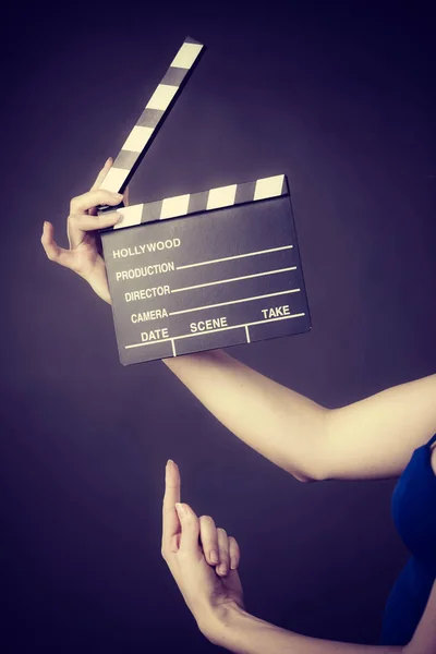 Woman holding professional film slate, movie clapper board. Hollywood production objects concept. Studio shot on black background.