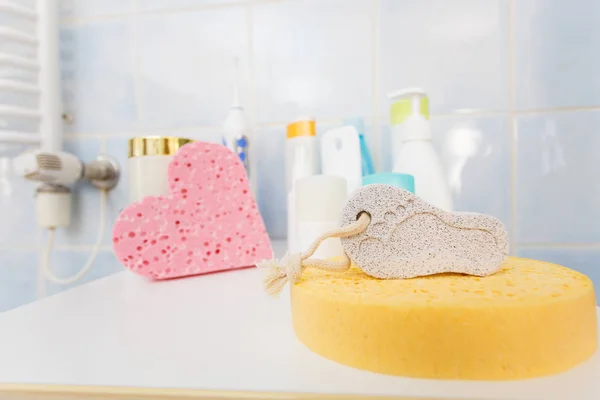 Pumice stone in foot shape on yellow bath sponge. Bathroom objects. Pedicure essentials.