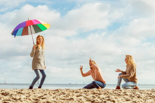 Birlikte harika vakit geçiren üç kadın. Renkli bir şemsiye tutan bir kadın.