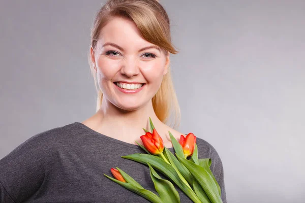 Happiness and satisfaction with life. Blonde woman wearing eyewear with single red green tulip. Happy joy girl feeling spring time holding beautiful flower.